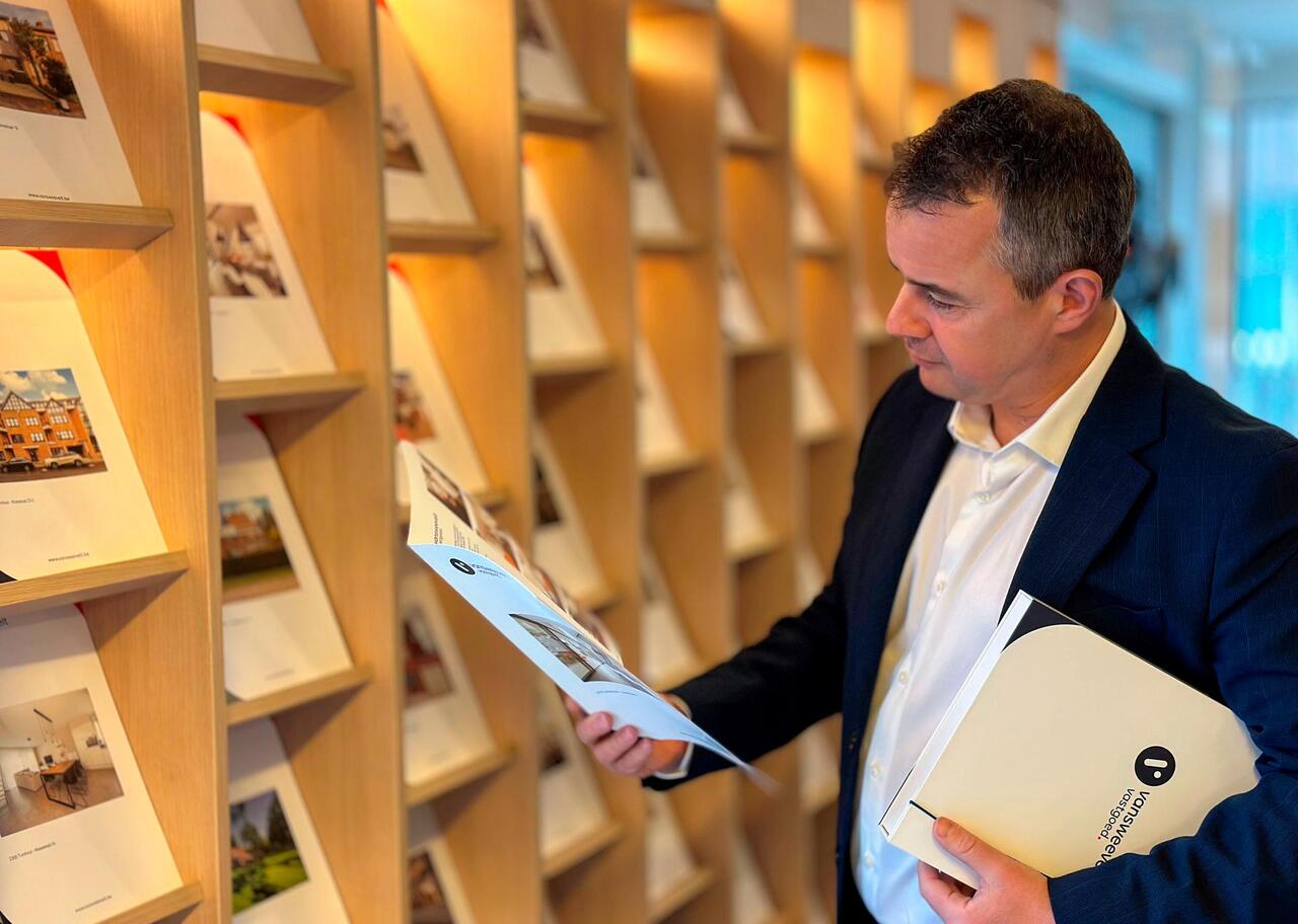 Makelaar van Vansweevelt vastgoed die een brochure bekijkt 